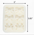 A pale mint green silicone mold with six embossed bow-shaped cavities, shown against a plain white background.