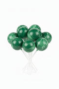 A group of round green cake pops on sticks, packaged inside a clear plastic bag.